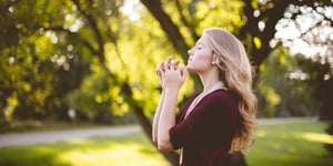 A woman praying on a sunny day.
