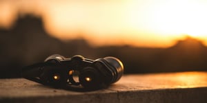 Binoculars on a ledge looking out at a sunset.