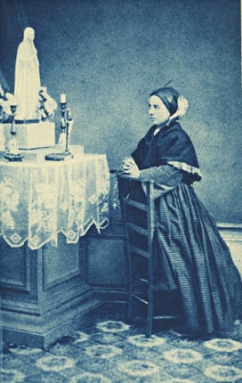St. Bernadette holding her Rosary and praying.
