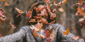 Woman throwing leaves into the air. 
