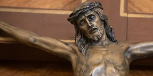 Brown statue of Jesus on a wooden cross with a crown of thorns. 
