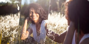 A woman happy and looking in a mirror.