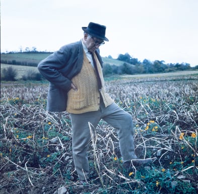 Catholic Poet Patrick Kavanagh walking through a flower field.