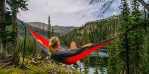 Woman in a hammock relaxing and taking in a nature scene. 