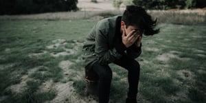 Man kneeling and crying through his suffering.