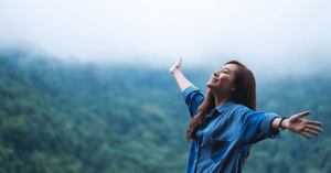 smiling woman with open arms gazing at the sky