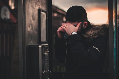 man in london using payphone at night