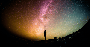 a lone person looks up at the universe