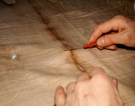Nun's hands removing single thread from the Shroud of Turin.