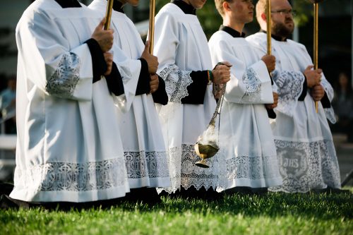 altar servers kneeling in field with thurible and candles