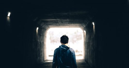 man in blue sweater stand in dark tunnel
