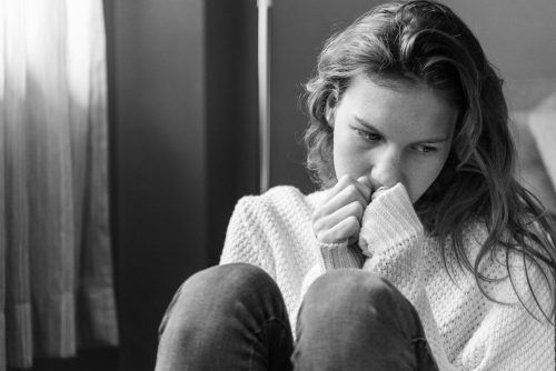 greyscale, woman sitting hunched in a corner