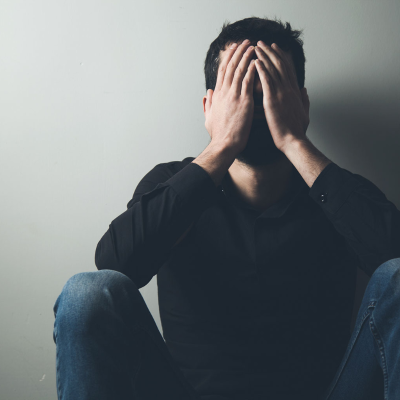 Man suffering and covering his face.