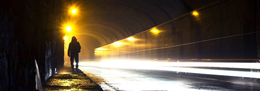 A man walking along a very lit tunnel.