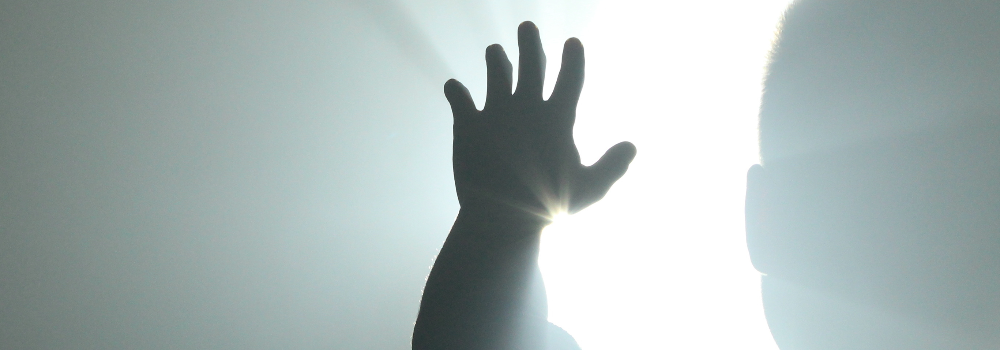 A man reaching his hand towards a light.