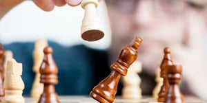 A hand moving a chess piece signifying intelligence