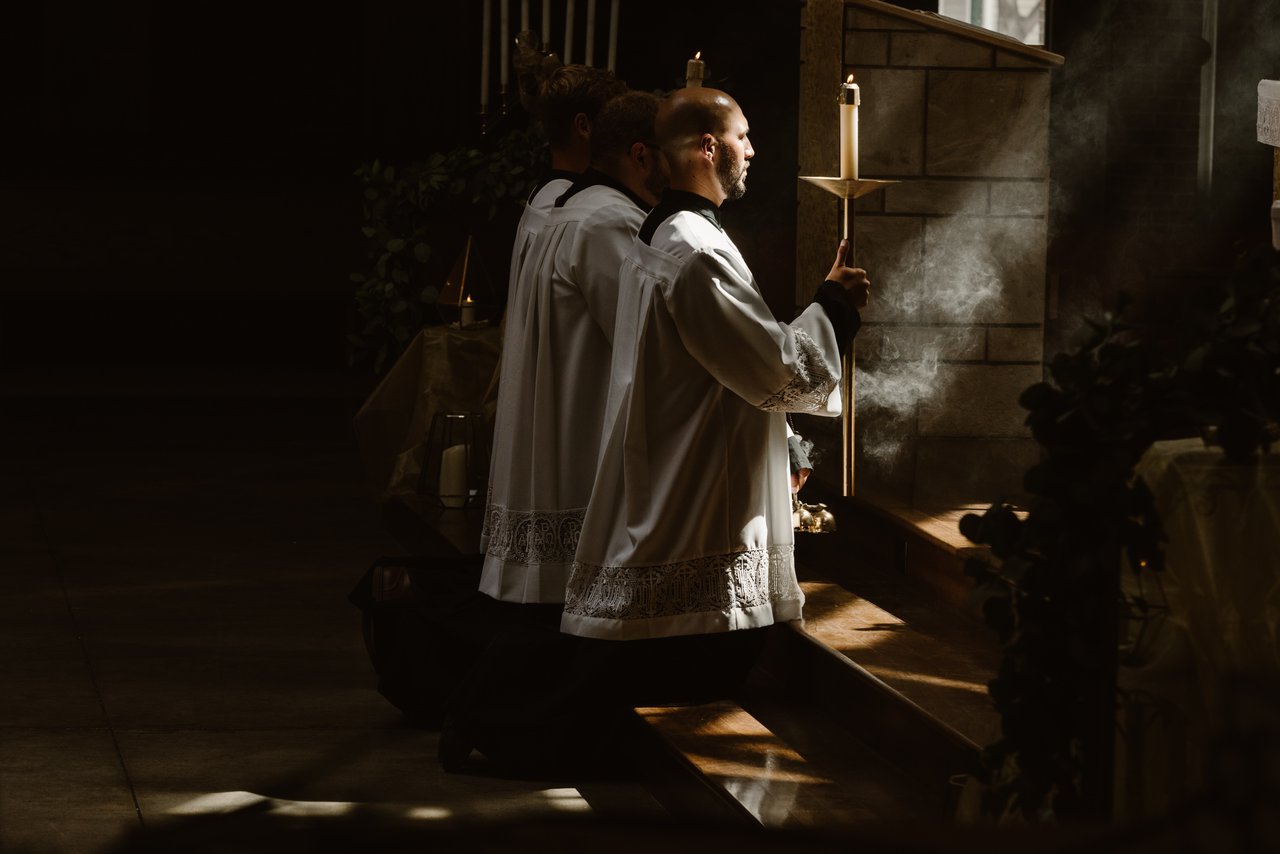 Men holding candles at alter.