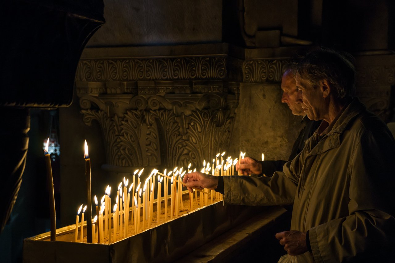 men lighting candles at an alter. 